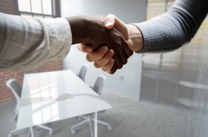 Two people shaking hands in office